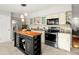 Kitchen area featuring modern black appliances, white cabinets, and butcher block island at 2228 Swedish Dr # 22, Clearwater, FL 33763