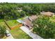 Aerial view of a house featuring a pool, well-manicured lawn, and lush surrounding trees at 2512 Rustic Oaks Dr, Lutz, FL 33559