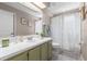 Bathroom with tiled floors, green cabinets, white counter, large mirror, and shower with curtain at 2512 Rustic Oaks Dr, Lutz, FL 33559