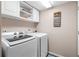 Laundry room featuring white appliances, overhead storage, and a decorative laundry sign at 2512 Rustic Oaks Dr, Lutz, FL 33559