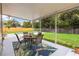 Charming covered patio with outdoor dining set overlooking green lawn and sparkling pool at 2512 Rustic Oaks Dr, Lutz, FL 33559