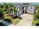 Lovely exterior view of a two-story gray home with a three-car garage and mature palm trees at 2517 Cumberland Cliff Dr, Ruskin, FL 33570