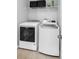 Well-lit laundry room with a washer and dryer, and shelving with storage bins above at 2517 Cumberland Cliff Dr, Ruskin, FL 33570