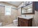 Bathroom featuring stylish vanity, granite counter and travertine walls at 2675 Firestone Dr, Clearwater, FL 33761
