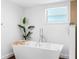 Bright white bathroom with a standalone tub, wood floors and sleek modern finishes at 326 176Th Avenue Cir, Redington Shores, FL 33708