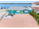 Waterfront home featuring a bright blue exterior, lush landscaping, and a brick paved driveway at 326 176Th Avenue Cir, Redington Shores, FL 33708