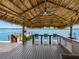 Home boasts a tiki hut with an outdoor kitchen, ceiling fan, and seating, perfect for entertaining with waterfront views at 326 176Th Avenue Cir, Redington Shores, FL 33708