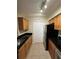 Efficient kitchen with light wood cabinets, black countertops, and stainless steel refrigerator at 3260 Haviland Ct # 202, Palm Harbor, FL 34684