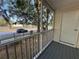 View from a screened-in patio with white railings showing the street and surrounding trees at 3260 Haviland Ct # 202, Palm Harbor, FL 34684