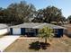 Aerial view of a charming blue home featuring a landscaped front yard and a garage on the left side at 3530 Umber Rd, Holiday, FL 34691