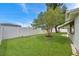 Beautiful backyard with manicured lawn, mature tree, and white vinyl fence, offering privacy at 3716 Carioca Rd, Holiday, FL 34691