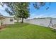 Spacious backyard with lush green grass, mature tree, white fencing, and a swing set at 3716 Carioca Rd, Holiday, FL 34691