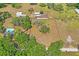 An aerial view of the property showcasing the home, surrounding land, mature trees, and neighboring properties at 39427 Comstock Ln, Zephyrhills, FL 33540