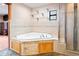 The bathroom displays a corner soaking tub surrounded by neutral tiling and sleek glass shelving at 39427 Comstock Ln, Zephyrhills, FL 33540