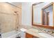 The full bathroom includes tiled shower-tub, granite-topped vanity, and wood-framed mirror at 39427 Comstock Ln, Zephyrhills, FL 33540