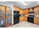Charming kitchen with wood cabinets, black appliances, frosted pantry, and tile flooring at 39427 Comstock Ln, Zephyrhills, FL 33540