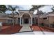 Elegant home with a columned entryway, arched windows, tile roof, and mature palm trees at 4872 Silverthorne Ct, Oldsmar, FL 34677