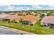 Aerial view of the backyard featuring a screened lanai, lush green grass, and tropical palms with a lake view at 4949 Marble Springs Cir, Wimauma, FL 33598
