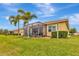 Home exterior features a screen enclosed patio, lush green lawn, and mature palm trees at 4949 Marble Springs Cir, Wimauma, FL 33598