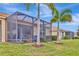 Exterior screened-in patio area with lawn and tropical trees beyond at 4949 Marble Springs Cir, Wimauma, FL 33598