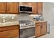 Stainless steel appliances and modern cooktop complement the granite countertops and mosaic backsplash at 4949 Marble Springs Cir, Wimauma, FL 33598