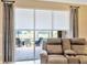 Living room with a sliding glass door with curtains and a view of the patio and pond at 4949 Marble Springs Cir, Wimauma, FL 33598