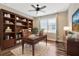 Spacious office with hardwood floors, built-in bookshelves, and a wooden desk with tufted leather chair at 4949 Marble Springs Cir, Wimauma, FL 33598