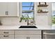 Close-up of kitchen sink featuring white subway tile backsplash, stainless steel appliances, and floating shelves at 5437 Del Coronado Dr, Apollo Beach, FL 33572