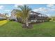 Expansive backyard featuring lush green grass, a screened-in patio, and beautiful landscaping at 5477 Wayfarer Ave, Apollo Beach, FL 33572