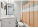 Bright bathroom with a white vanity, toilet, and a shower with a modern orange and white curtain at 5477 Wayfarer Ave, Apollo Beach, FL 33572
