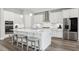 Stylish kitchen boasting white cabinetry, stainless steel appliances, a center island with seating, and sleek wood flooring at 5477 Wayfarer Ave, Apollo Beach, FL 33572