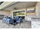 A cozy covered patio features a ceiling fan and outdoor furniture with a fireplace and exterior kitchen at 5477 Wayfarer Ave, Apollo Beach, FL 33572