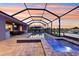Screened-in pool and spa with outdoor kitchen, and lounge seating under a sunset at 5477 Wayfarer Ave, Apollo Beach, FL 33572