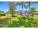 Green lawn with a view of the pool and lanai, as well as tropical landscaping at 6104 Cognac Cir, Lutz, FL 33558