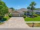 Beautiful home featuring a three-car garage, paver driveway, manicured lawn, and mature landscaping at 6104 Cognac Cir, Lutz, FL 33558