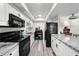 Kitchen featuring white cabinets, black appliances and stone countertops at 710 N Village N Dr # 102, St Petersburg, FL 33716