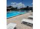 Community pool with white lounge chairs and a tennis court in the background at 710 N Village N Dr # 102, St Petersburg, FL 33716