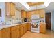 Well-lit kitchen featuring wooden cabinets, white appliances, and wood-look flooring at 7534 Culberson Dr, Port Richey, FL 34668