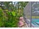 Inviting backyard features lush tropical landscaping and access to a screened-in pool area at 7649 Nottinghill Sky Dr, Apollo Beach, FL 33572