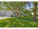 Charming single-story home featuring a well-manicured lawn and beautiful landscaping, including a large shade tree at 7649 Nottinghill Sky Dr, Apollo Beach, FL 33572