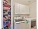 Functional laundry room with washer and dryer and plenty of shelving at 7649 Nottinghill Sky Dr, Apollo Beach, FL 33572