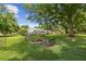 Lush backyard with a fire pit, mature trees, and an enclosed patio creates the perfect outdoor retreat at 1703 Ryan Dr, Lutz, FL 33549
