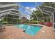 Screened pool with brick patio, complemented by an umbrella and lush landscaping at 1703 Ryan Dr, Lutz, FL 33549