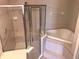 Bathroom with glass enclosed shower and corner tub with decorative tile surround at 10402 Tulip Field Way, Riverview, FL 33578