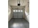 Empty garage with a closed overhead garage door, painted floor and white block walls at 10402 Tulip Field Way, Riverview, FL 33578