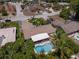 Aerial view of a single-Gathering home with tile roof, caged in back porch, and kidney-shaped pool surrounded by lush landscaping at 10515 Hetrick W Cir, Largo, FL 33774