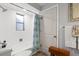 Bright bathroom offers a combination tub and shower with neutral tile and a beachy accent curtain at 10515 Hetrick W Cir, Largo, FL 33774