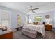 Bright bedroom featuring light blue walls, ceiling fan, two windows, and a queen size bed at 10515 Hetrick W Cir, Largo, FL 33774