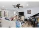 Bright living room featuring wood floors, white furniture, a ceiling fan, and a piano at 10515 Hetrick W Cir, Largo, FL 33774