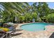 This backyard features a private pool, lush landscaping, and lounge chairs for ultimate relaxation at 10515 Hetrick W Cir, Largo, FL 33774